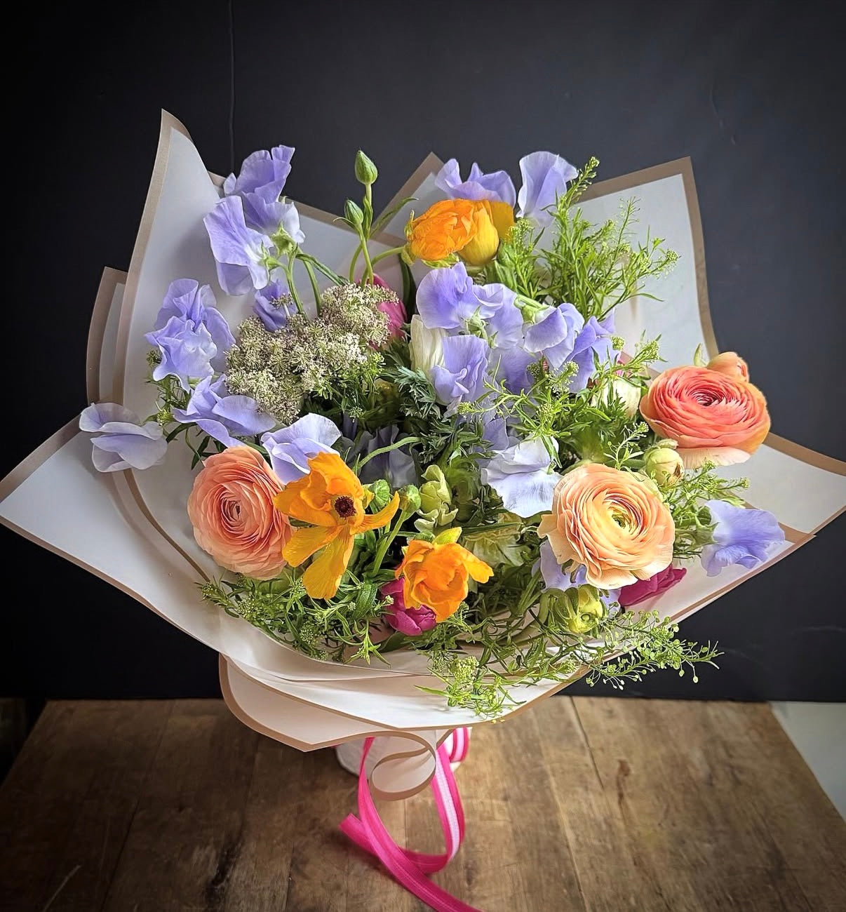 Alaric Flowers NYC Aurora bouquet — Ranunculus, Sweet Pea and Cosmos in joyful purple, orange and peach, perfect for birthdays.