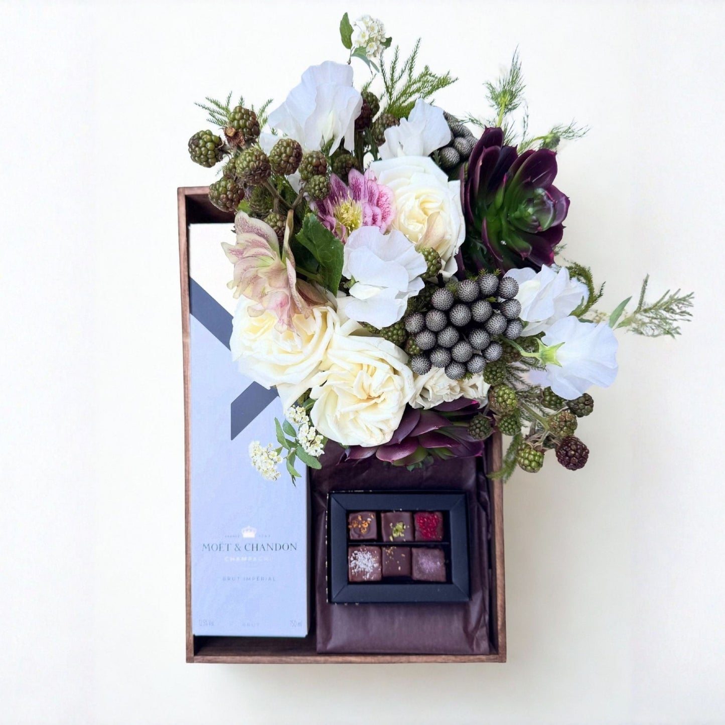 Floral arrangement with a small box of chocolates and Moet champagne on a white background