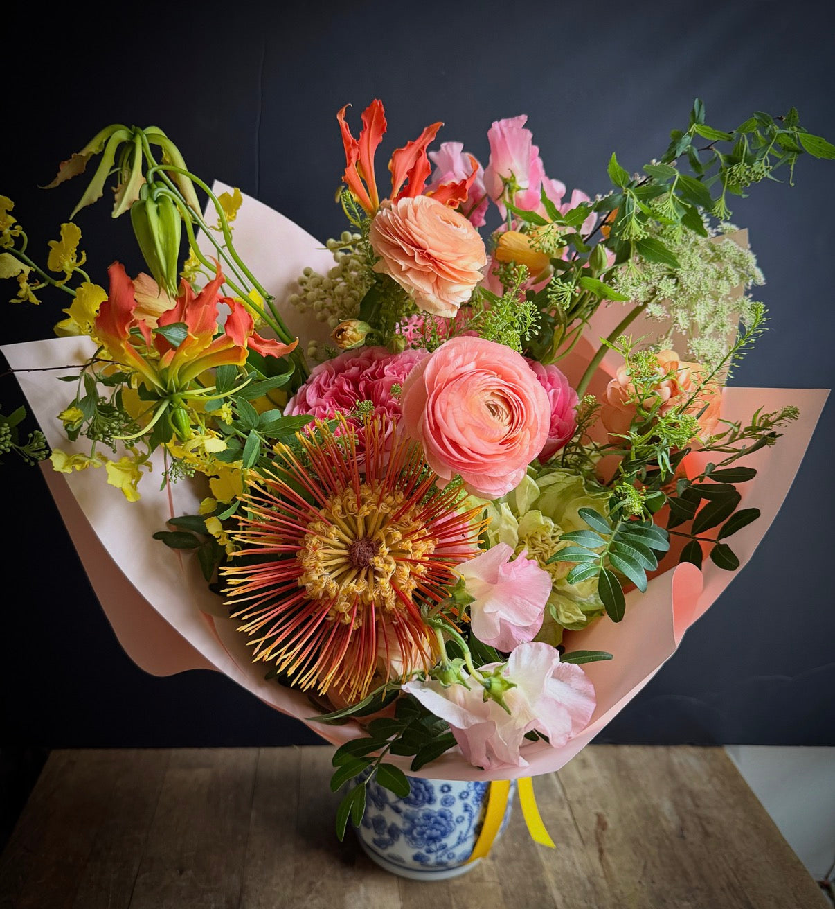 Alaric Flowers NYC Becca bouquet — vibrant Ranunculus, Gloriosa and Roses in pink and peach, perfect for birthdays.