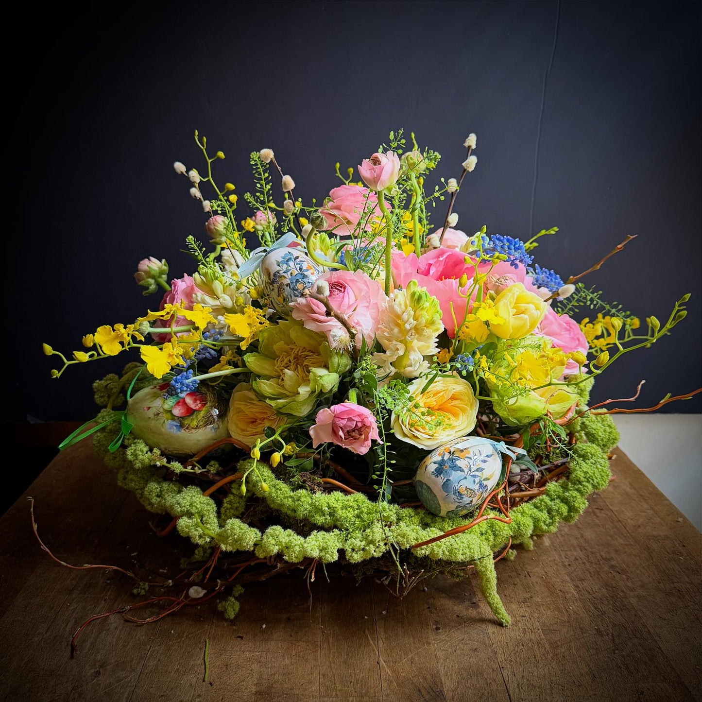 Colorful flower arrangement on a wooden surface with a dark background