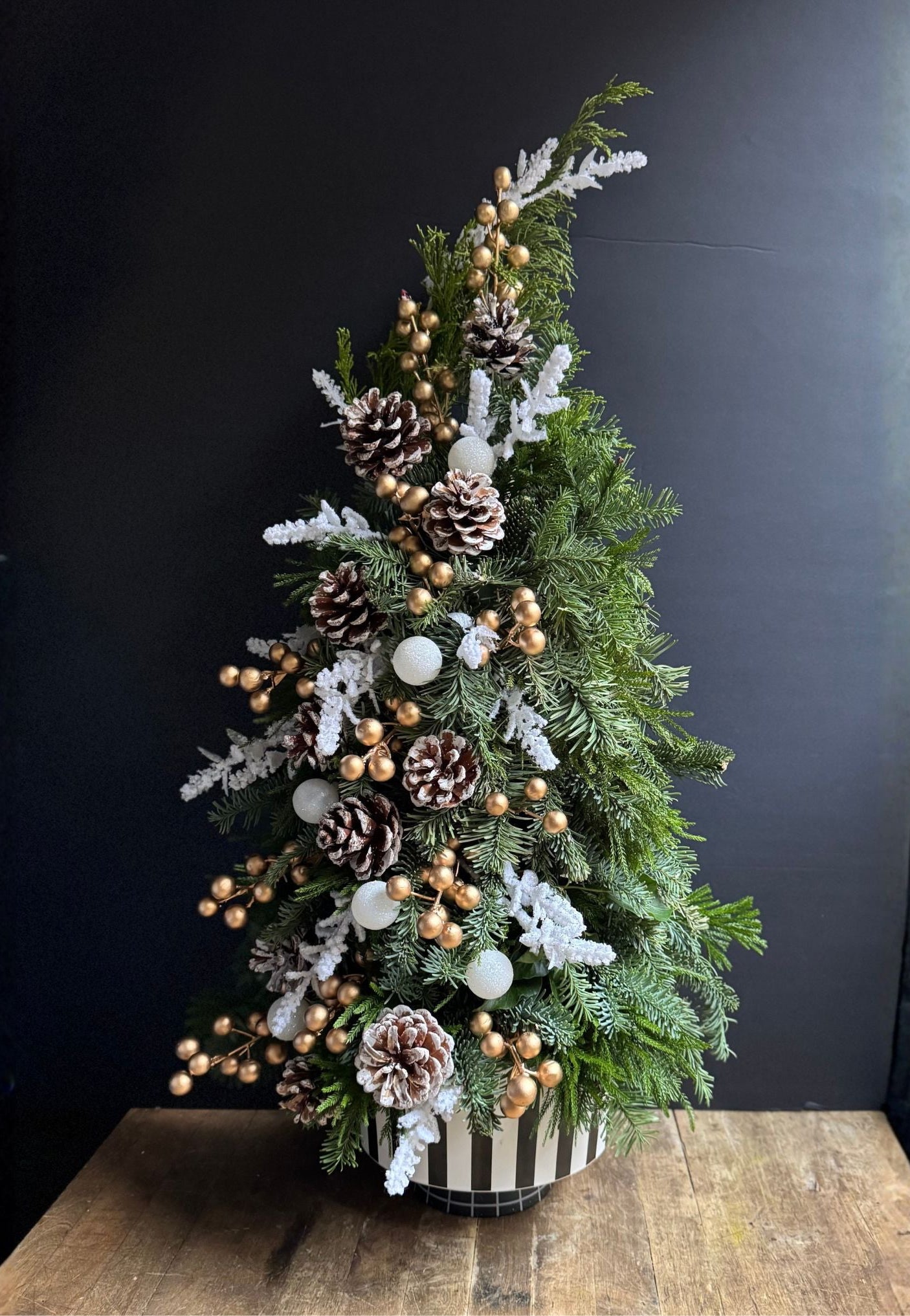 Decorative Christmas tree with ornaments on a wooden table against a dark background